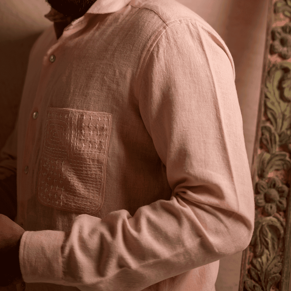 Close-up of a person wearing a traditional pastel pink kurta with embroidery.