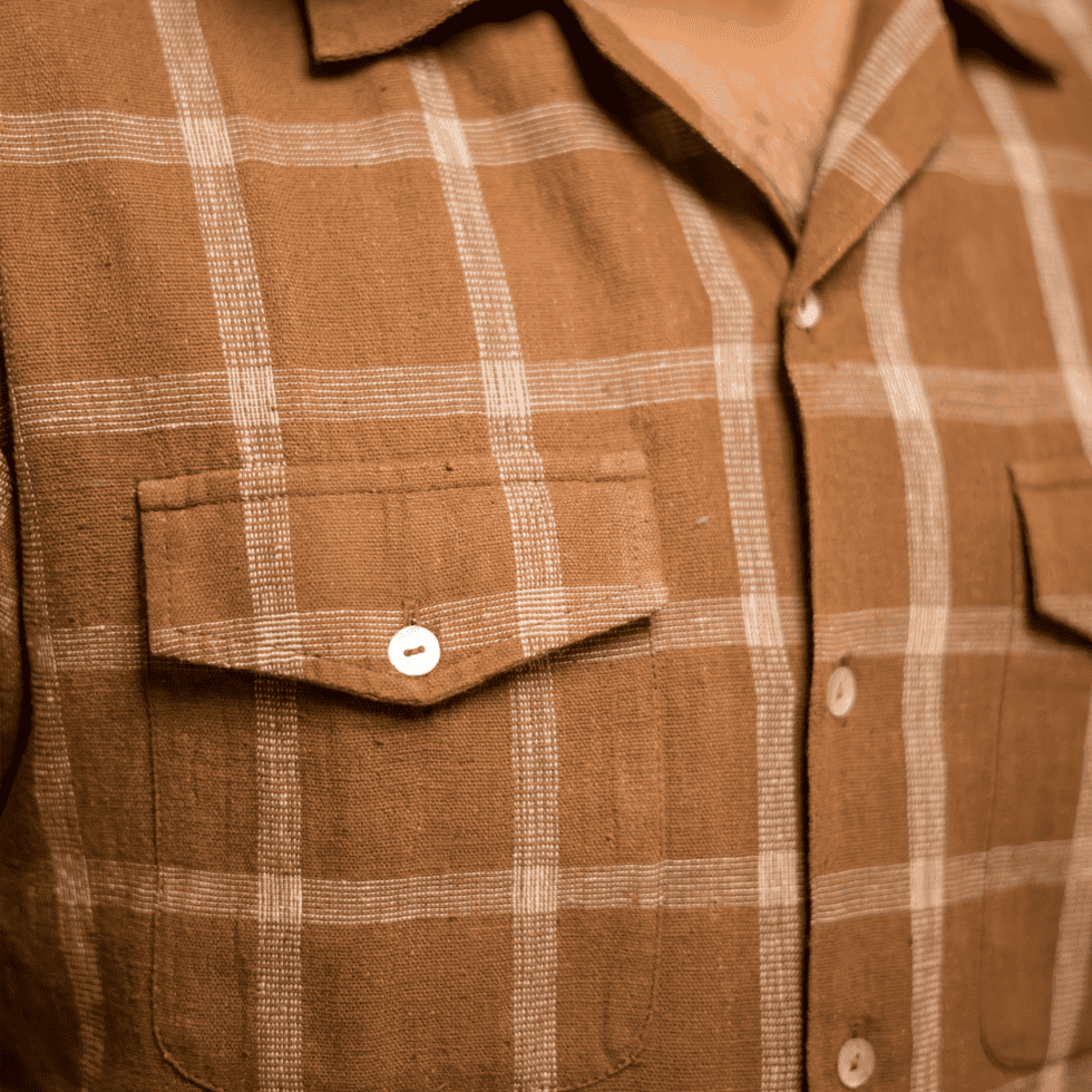 Close-up of a brown checkered shirt with chest pockets and white buttons.