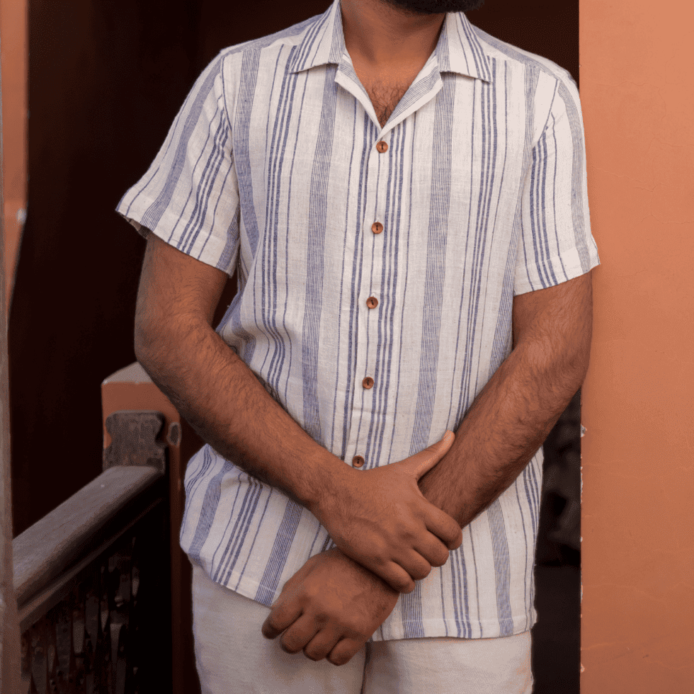 Man wearing a striped short-sleeve shirt standing outdoors.
