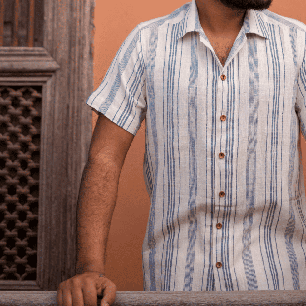 Man wearing a striped shirt standing near a wooden door.