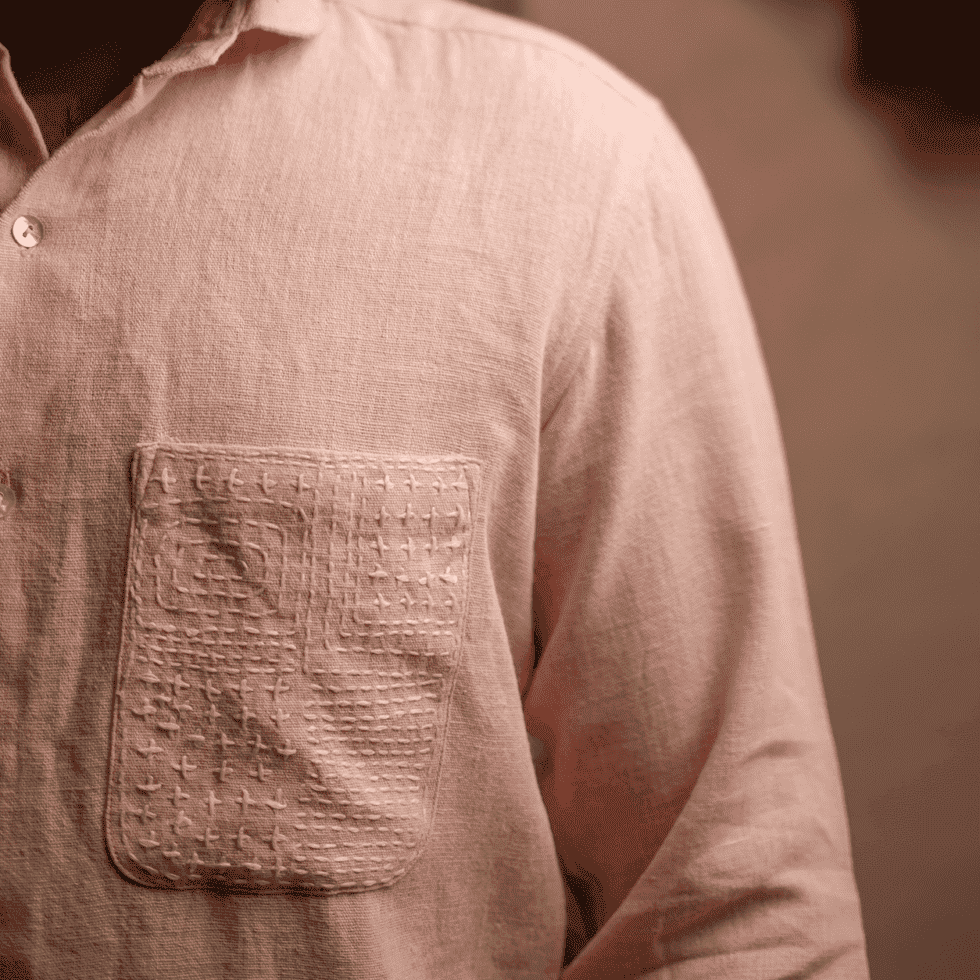 Close-up of a pastel pink linen shirt with a textured pocket detail.