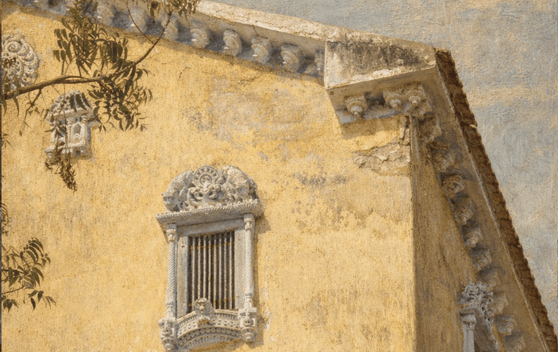 Historic yellow building with ornate window and decorative architectural details.